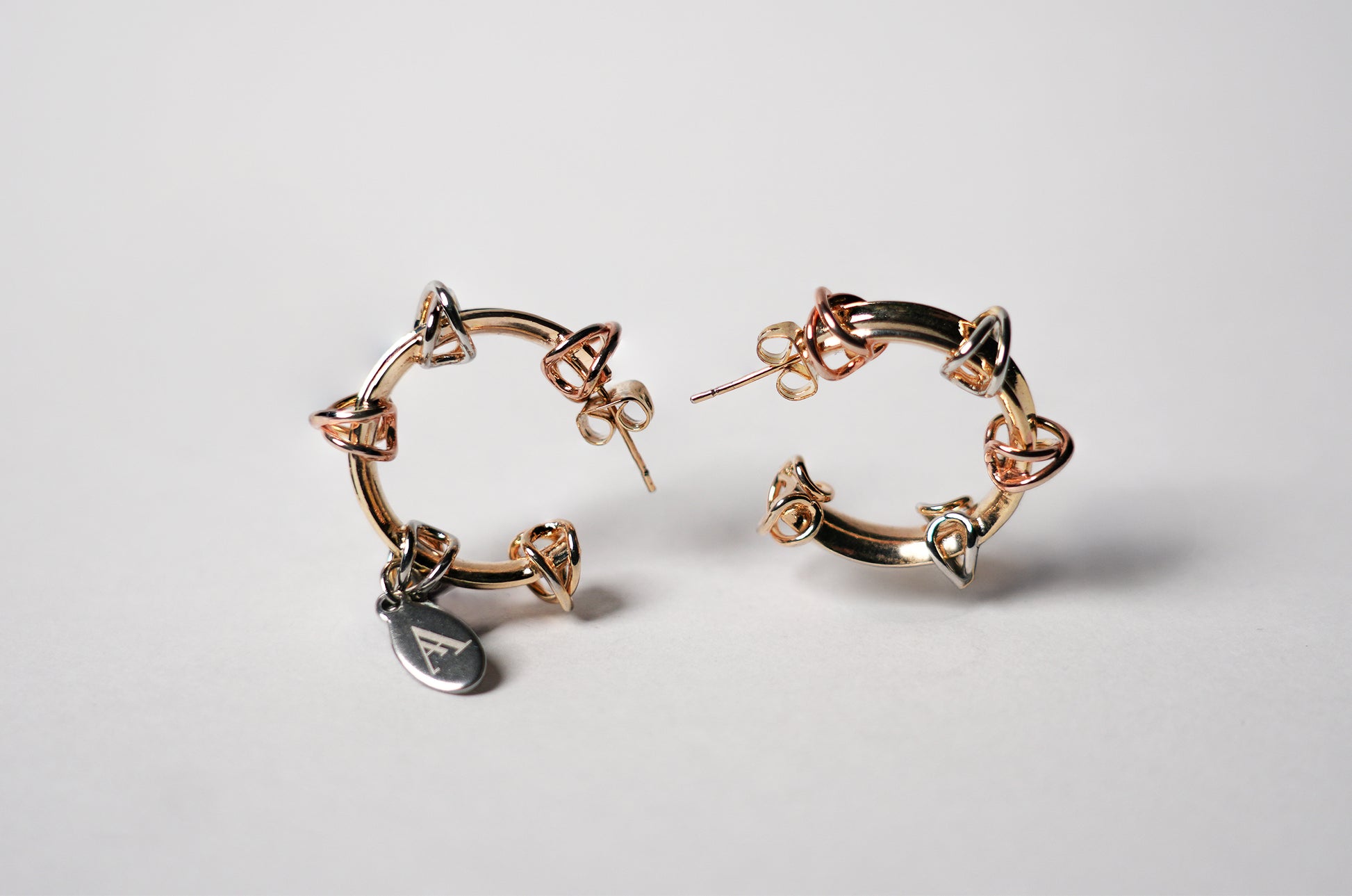 Aretes trinity de plata y gold-filled en diseño de aro con detalle triangular de la marca AMARYLLIS ANGLE